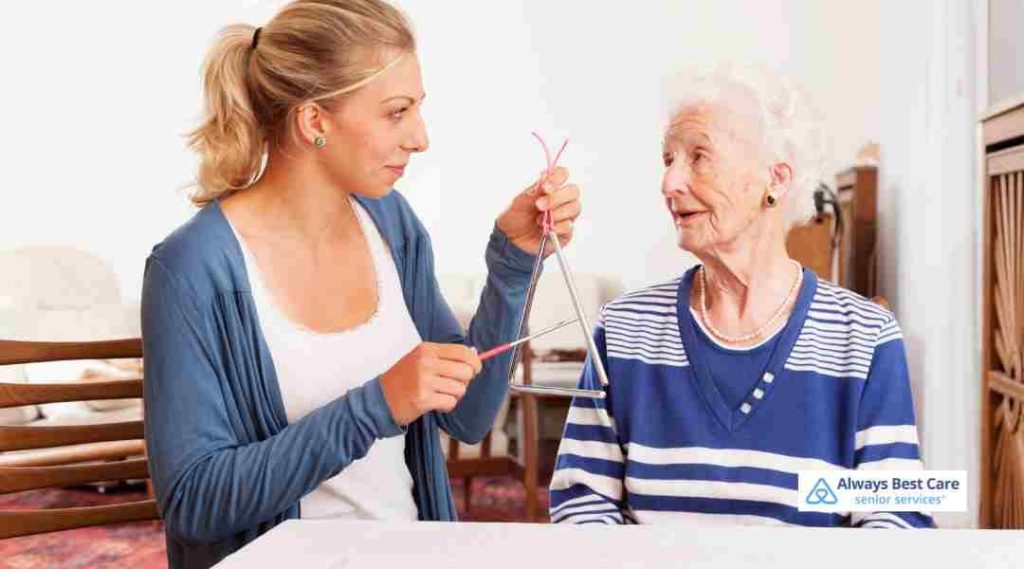 PROMOTING EMOTIONAL WELLNESS FOR SENIORS THROUGH MUSIC, ART, AND MOVEMENT IN ALEXANDRIA 6 CAREGIVER HELPING ELDERLY WOMAN WITH A CRAFT ACTIVITY, DEMONSTRATING PERSONALIZED IN HOME SENIOR CARE.”