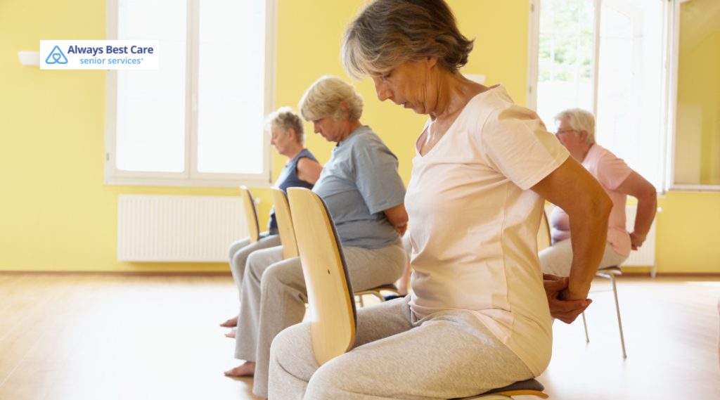 Caregiver guiding an older woman through arm exercises with light dumbbells.