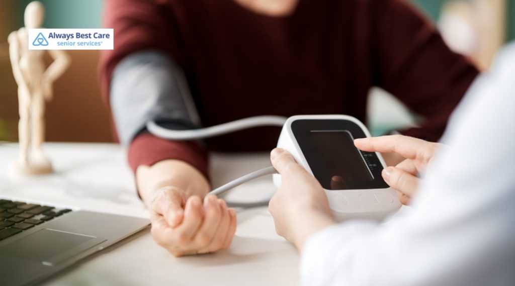 A caregiver measures an elderly person’s blood pressure using a digital monitor at home.