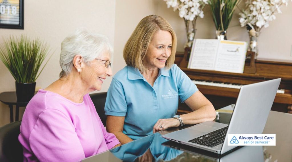 An Always Best Care Senior Services caregiver consulting with a senior woman at home, both seated at a table with a laptop, illustrating personalized support during in-home care planning.