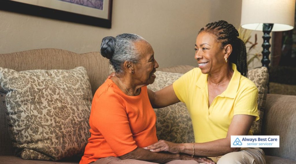 A caregiver from Always Best Care Senior Services gently comforting a senior woman in a cozy living room setting, reflecting empathy and personal connection during a home visit.