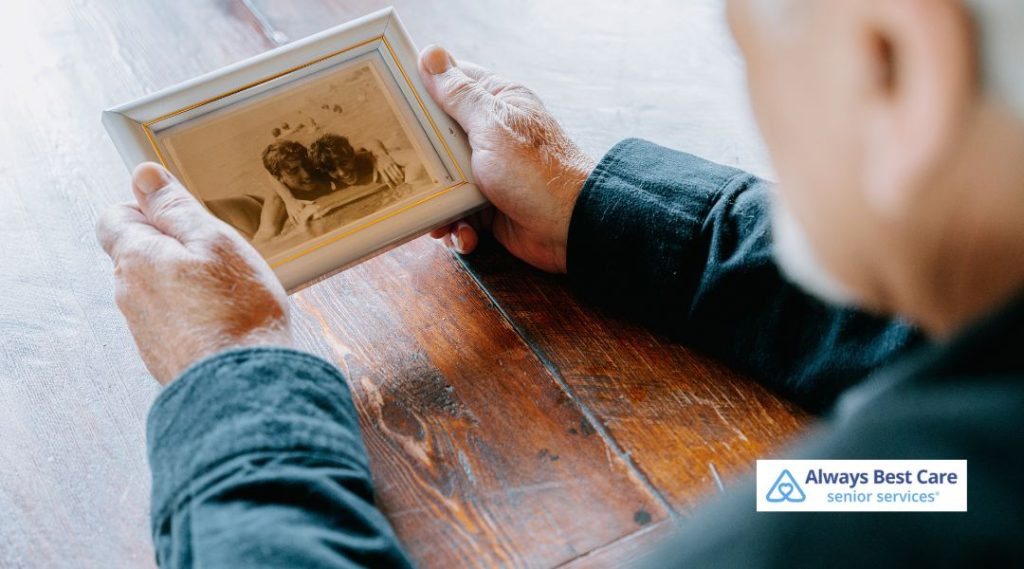 Older adult looking at a framed photograph during memory care and reminiscence therapy support.

