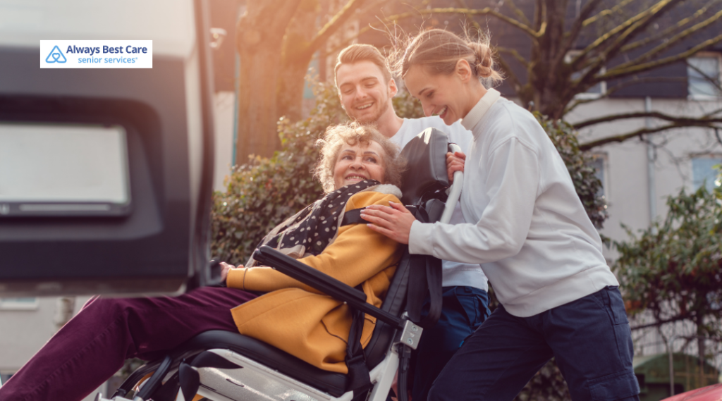 Family members assisting a senior woman in a wheelchair as they help her in and out of a vehicle.