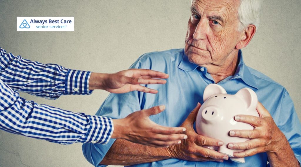 Elderly man clutching a piggy bank as hands reach for it.