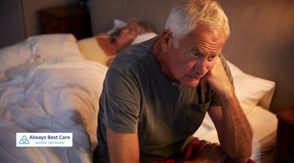 Worried elderly man sitting on the edge of the bed.
