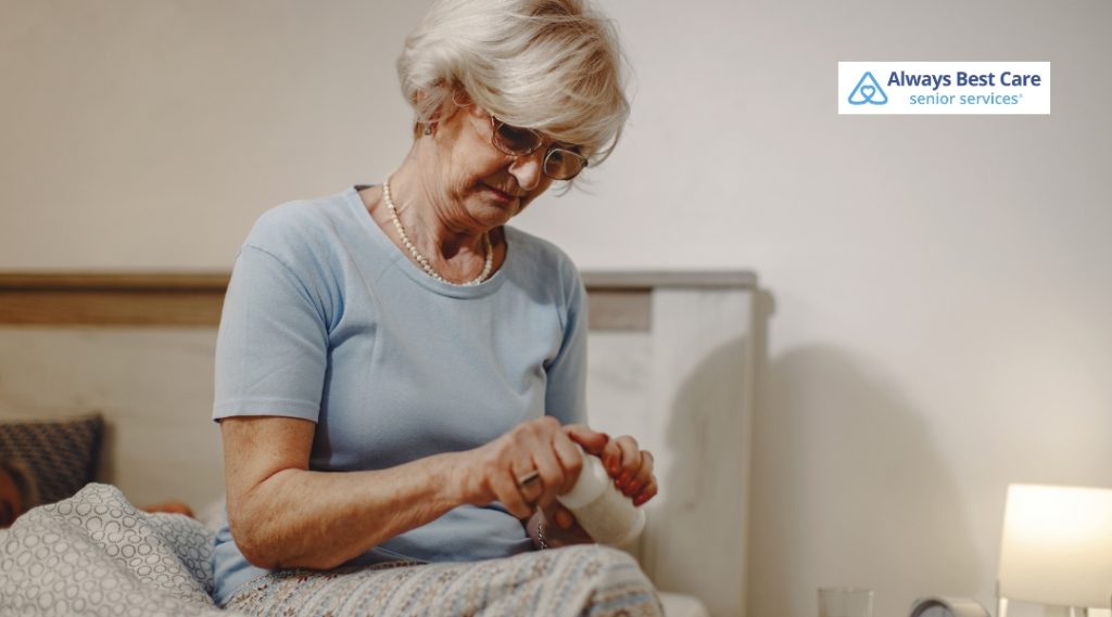 Elderly woman opening a pill bottle in her bedroom.