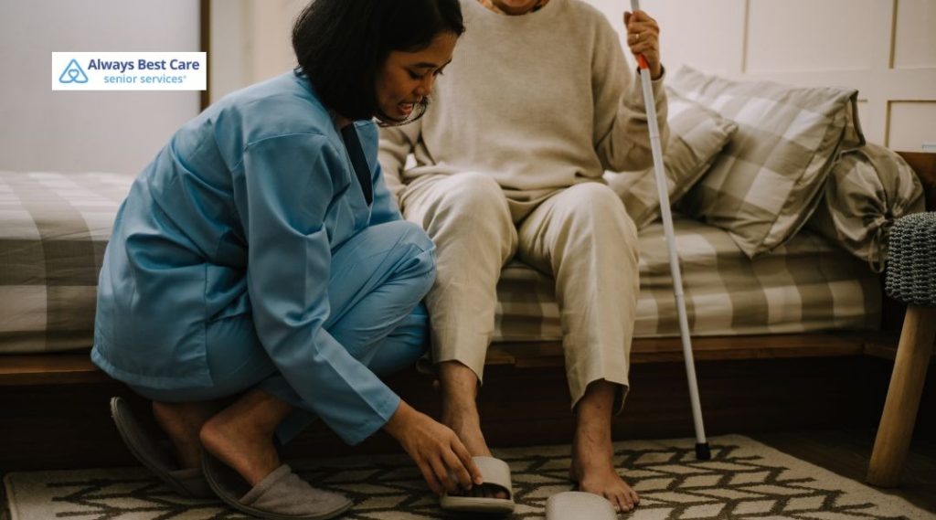 Caregiver supporting an older adult while standing up safely in the living room.