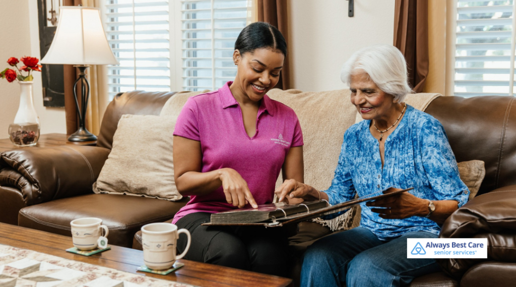 Caregiver and senior woman looking through a photo album together, sharing memories and conversation.