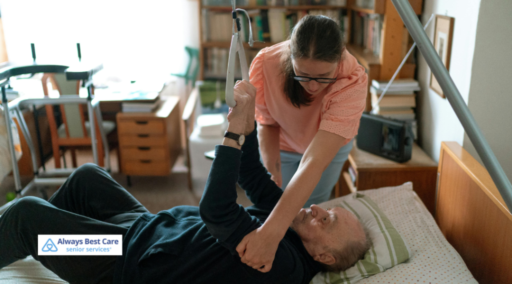 A caregiver assisting an elderly man in bed by helping him lift himself with a support bar, representing mobility assistance in home care.