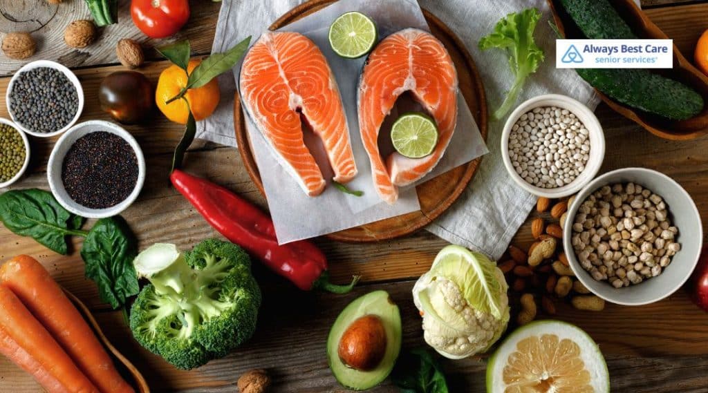 Fresh salmon fillets surrounded by vegetables, legumes, and healthy ingredients on a wooden table, symbolizing nutritious meal choices that support senior wellness.