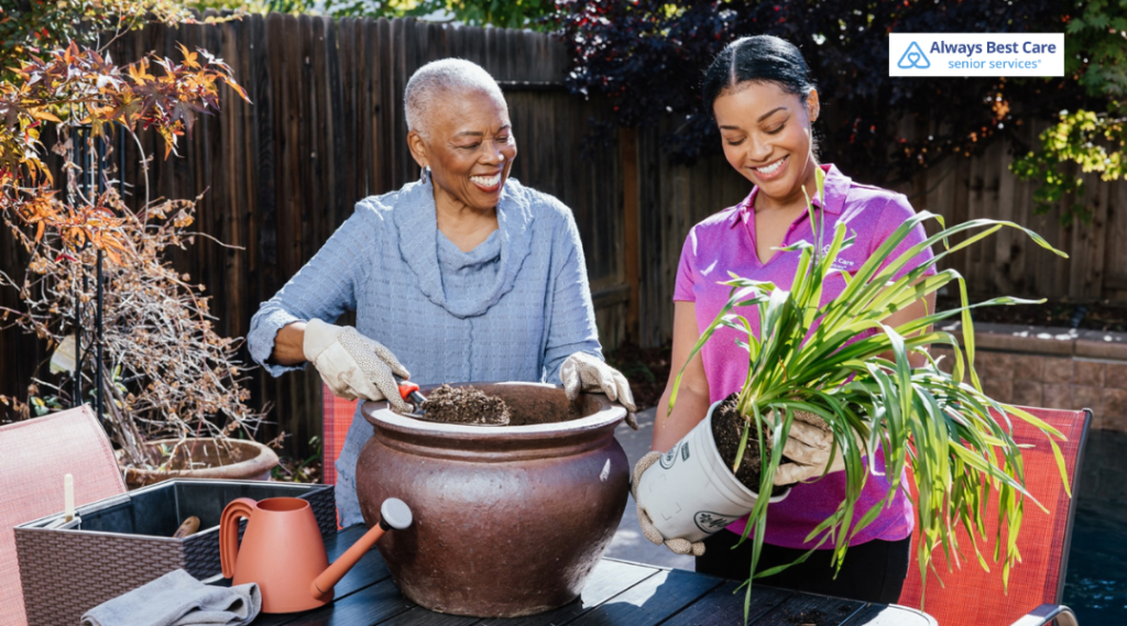 Caregiver and senior woman planting flowers together in a backyard garden, promoting activity and wellness.