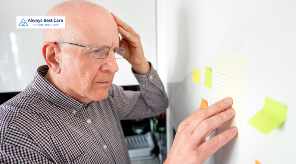 Older man holding his head while reading reminder notes posted on a refrigerator.