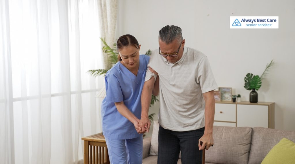 A caregiver assisting an elderly man, helping him stand while supporting him with a cane, in a bright and comfortable home setting, showing care and attentiveness.