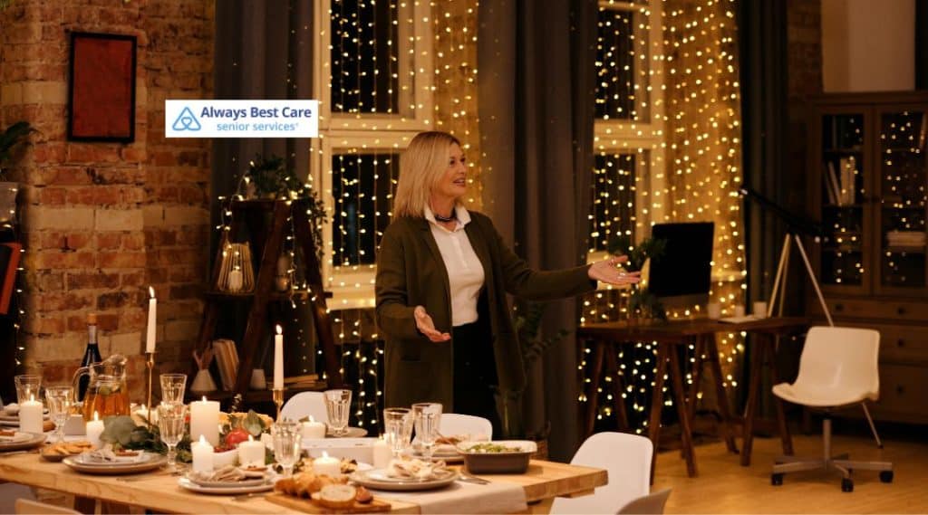 A woman gracefully welcomes guests into a beautifully decorated holiday dining room, showcasing a cozy and inviting atmosphere with twinkling lights and a well-set table, ready for a memorable meal.