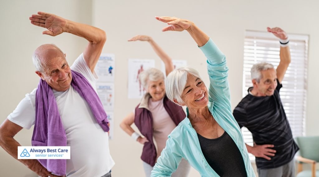 Group of seniors participating in a fitness class, stretching their arms and smiling while exercising together.