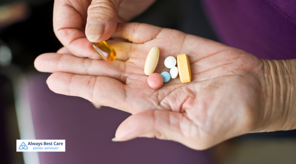A close-up view of a senior person's hand holding an assortment of colorful pills and a softgel capsule, illustrating medication management and support.