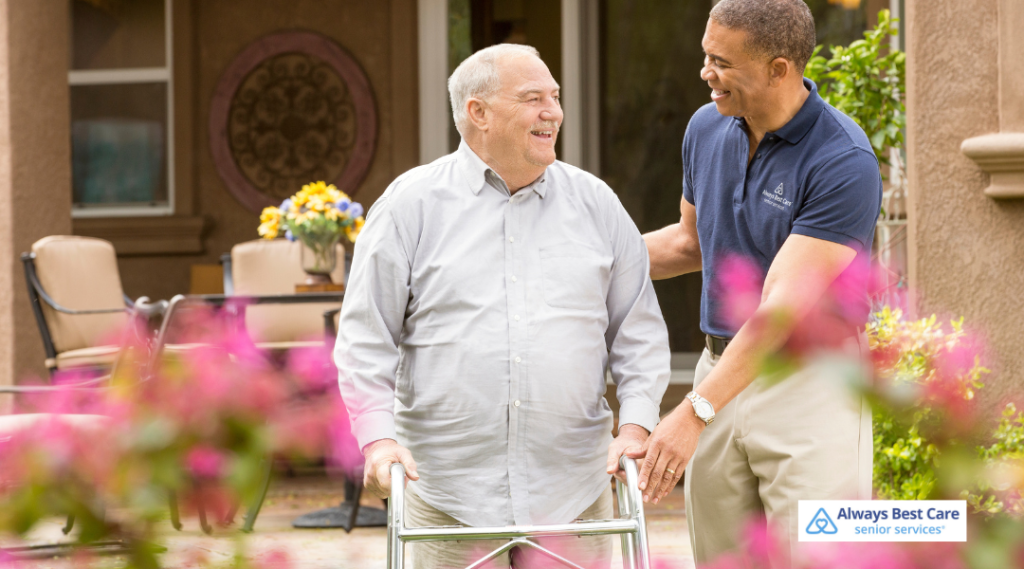 A caregiver from Always Best Care assists an elderly man in a wheelchair