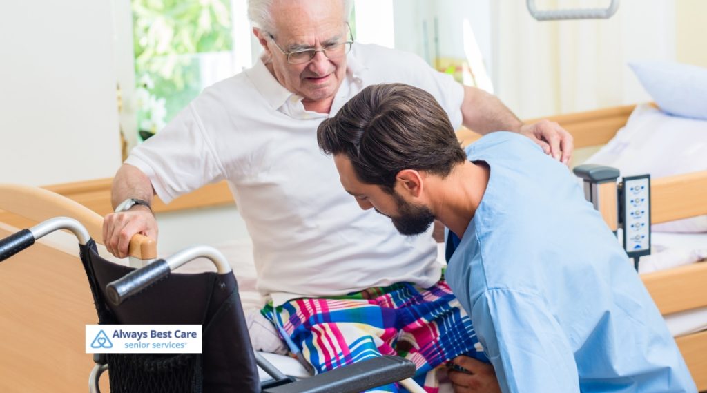 Caregiver assisting an elderly man in transitioning from bed to wheelchair, demonstrating personalized mobility support in a home care environment.