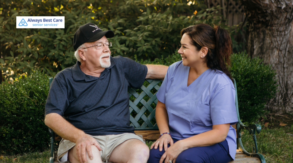  Caregiver and older woman sharing coffee and conversation at an outdoor patio table.