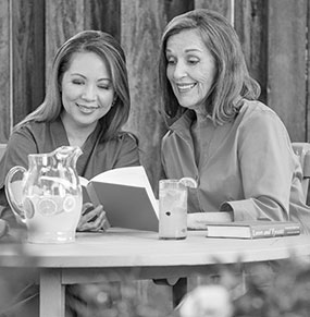 CAREGIVER AND SENIOR WOMAN READING A BOOK