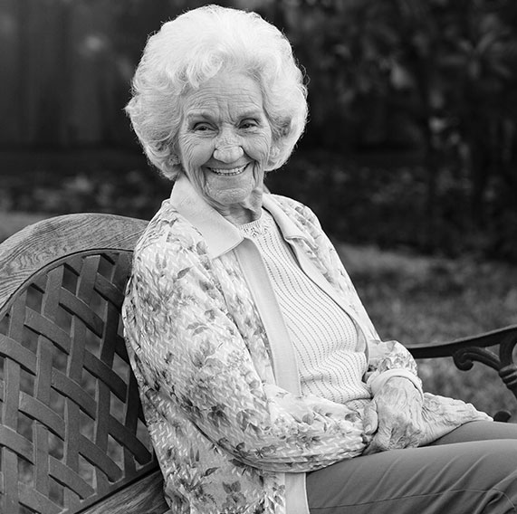 SENIOR WOMAN SITTING ON BENCH SMILING