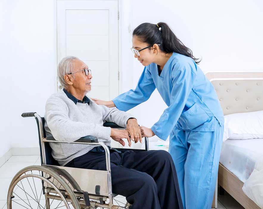 Senior old man in wheelchair assisted by caregiver