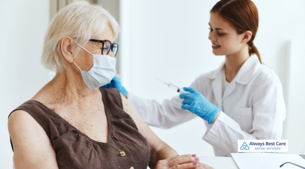 A senior man receiving a vaccine shot, with the healthcare provider in a blue medical uniform, administering the injection.