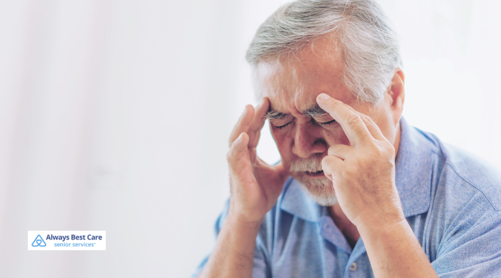 Senior man holding his temples while experiencing dizziness or headache at home.