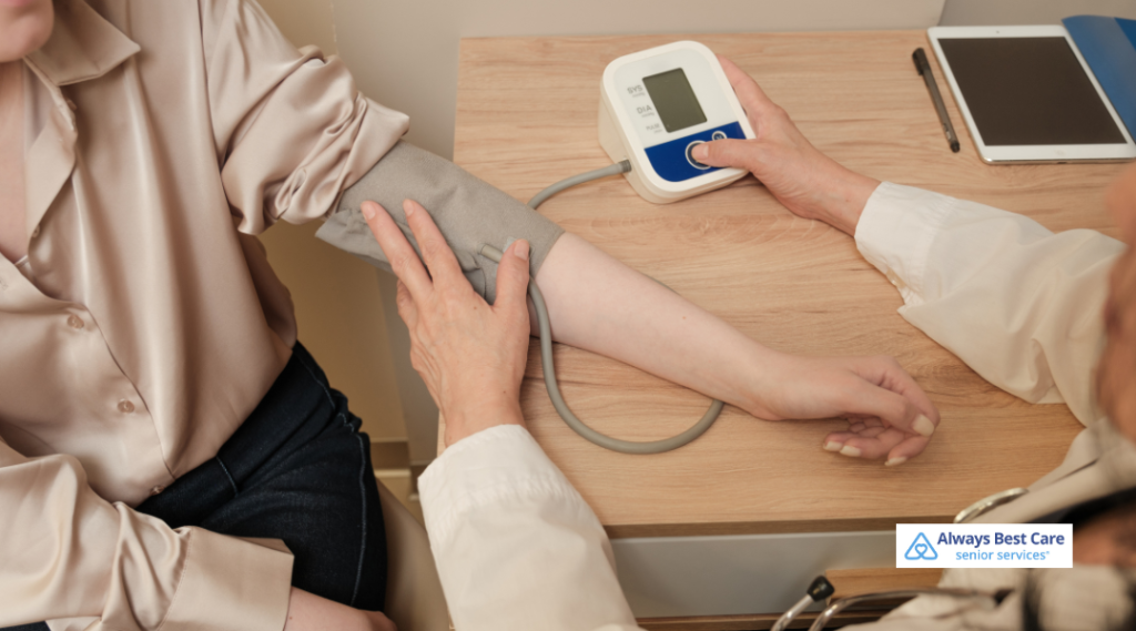 Care professional checking an older adult’s blood pressure using a digital monitor during an in-home health visit.