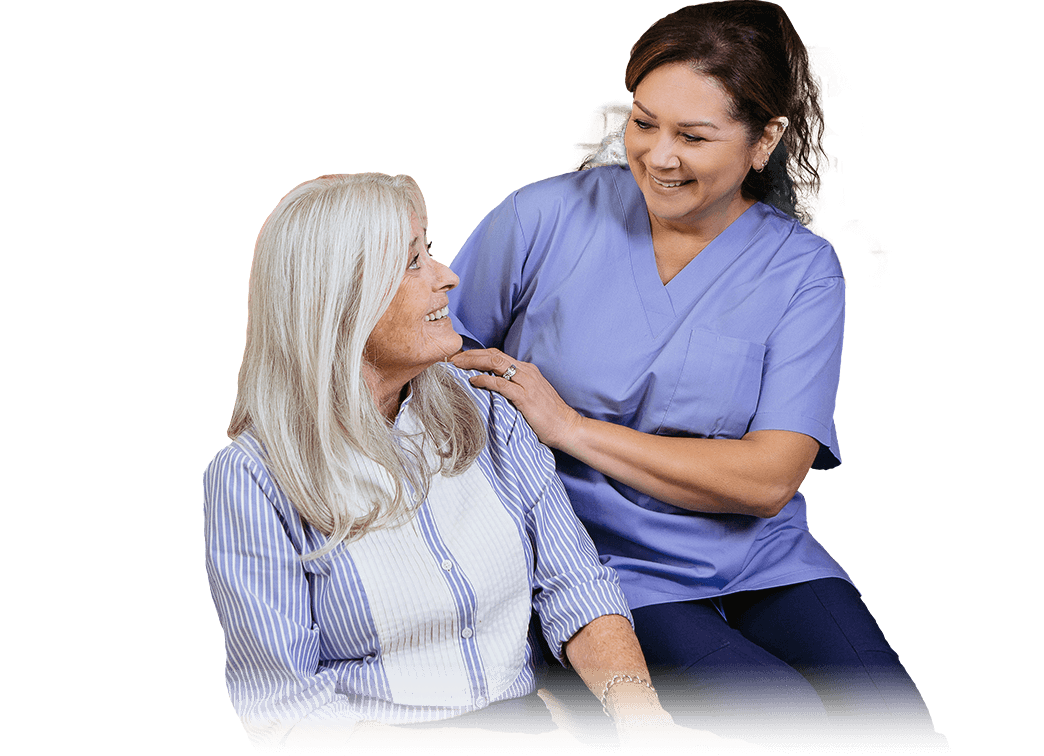 WOMAN CAREGIVER SITTING BESIDE A SENIOR WOMAN AND SMILING