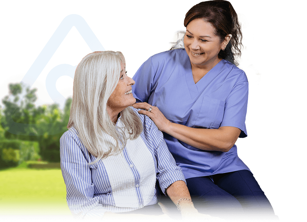 WOMAN CAREGIVER SITTING BESIDE A SENIOR WOMAN AND SMILING