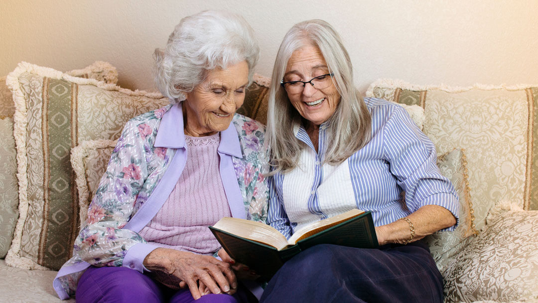 two senior woman reading book