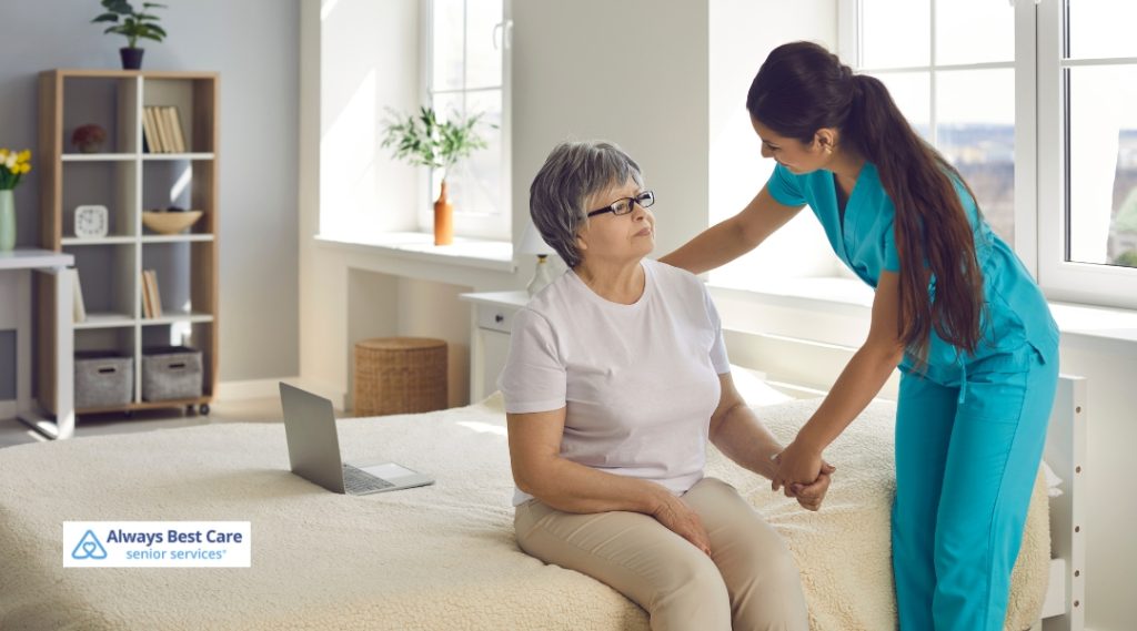 A caregiver assisting a senior woman in standing up from a bed with a caring touch, set in a well-lit, peaceful room.