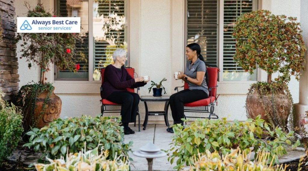 Senior caregiver providing companionship and conversation with an older adult outdoors at home.