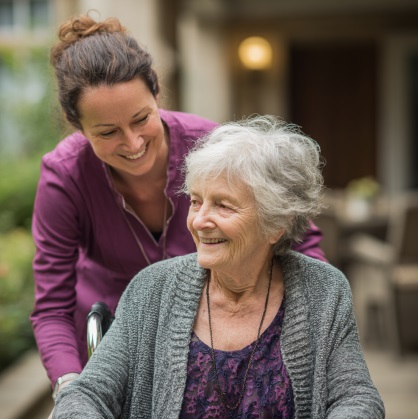 Caregiver assisting a senior woman in a wheelchair outdoors, sharing a warm moment of support in Sugar Land, TX.