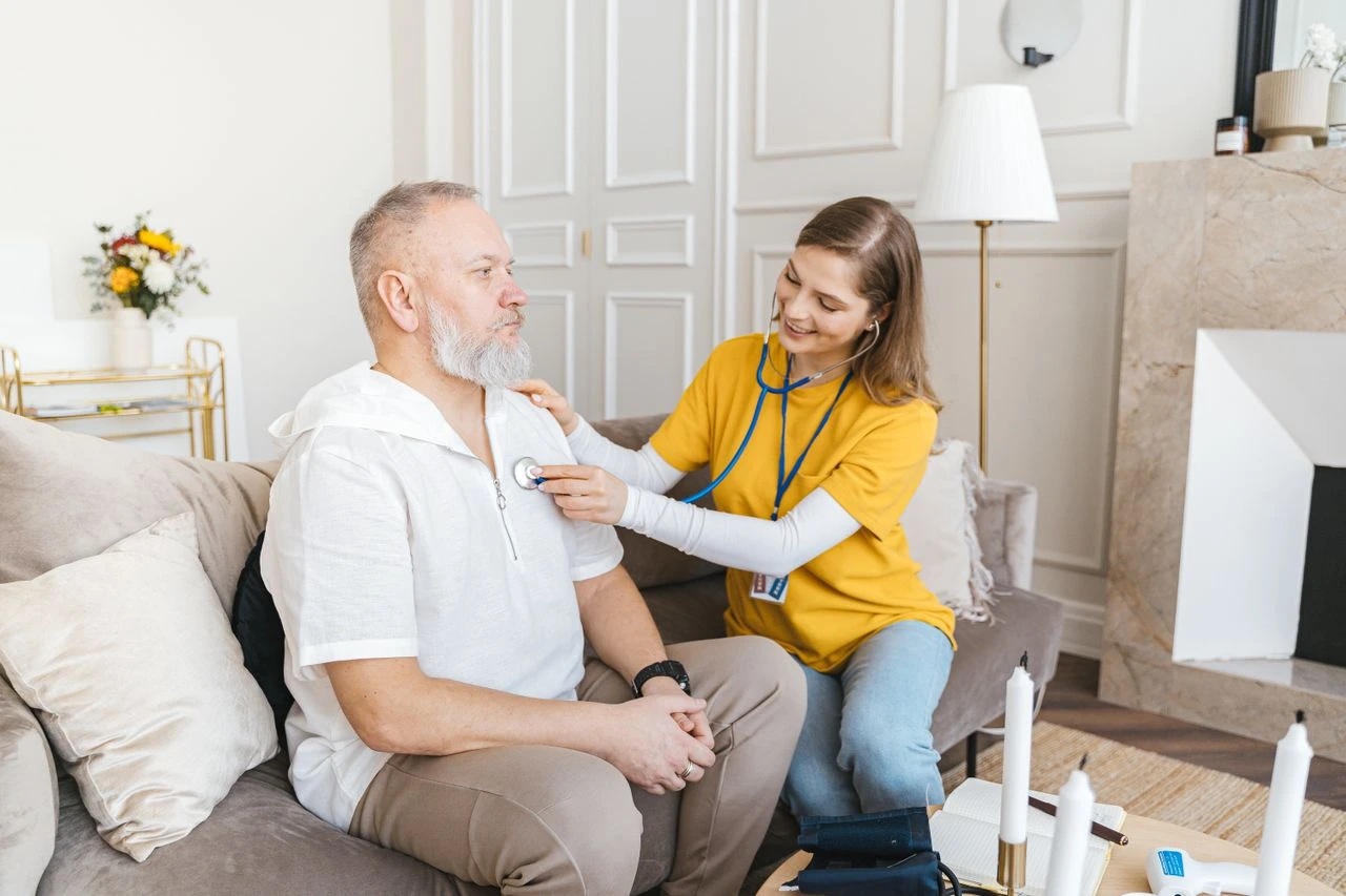 Home healthcare professional using a stethoscope to check an elderly man's heart during an in-home wellness visit for Home Care in Kingwood, TX.
