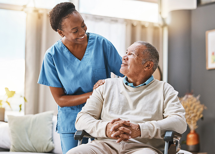 Professional caregiver assisting senior man in wheelchair at home, providing compassionate in-home care in Knoxville, TN