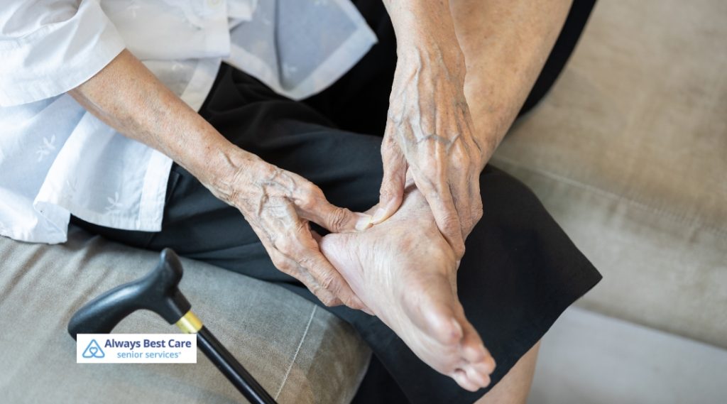 An elderly person examines their foot, with a walking cane resting nearby, likely 