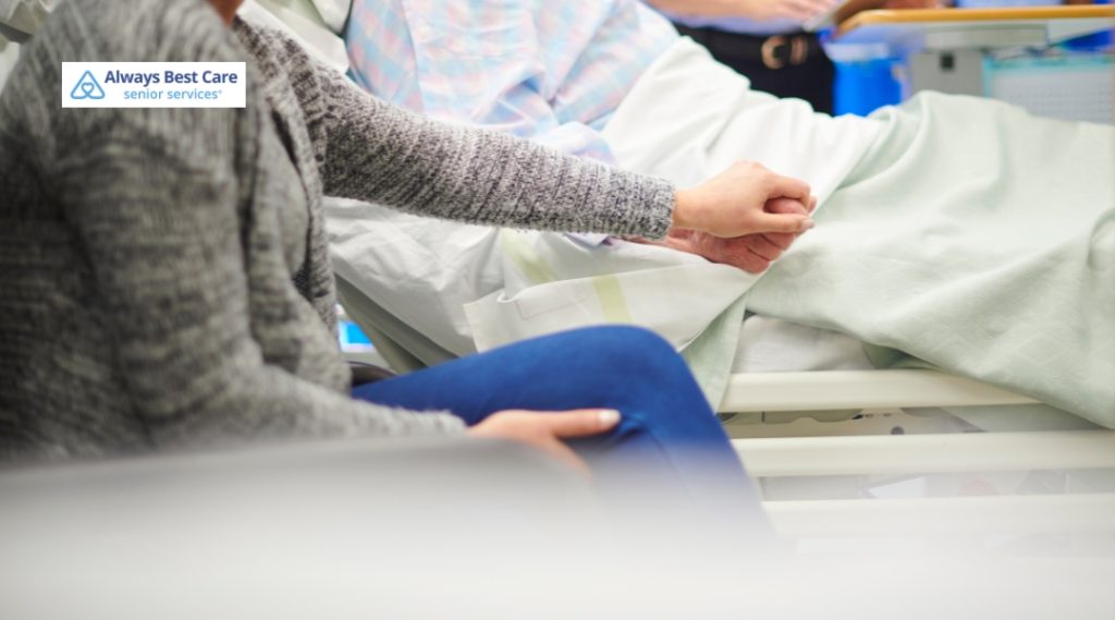 A family member holds the hand of a loved one in a hospital room, offering emotional support and comfort during a challenging time.