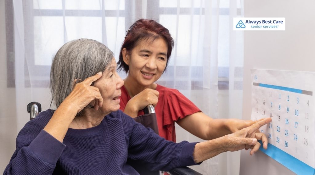 Three elderly individuals engage in a colorful block-stacking game at a table. One woman smiles at the camera, exuding joy and social interaction. The Always Best Care logo appears in the top left corner.