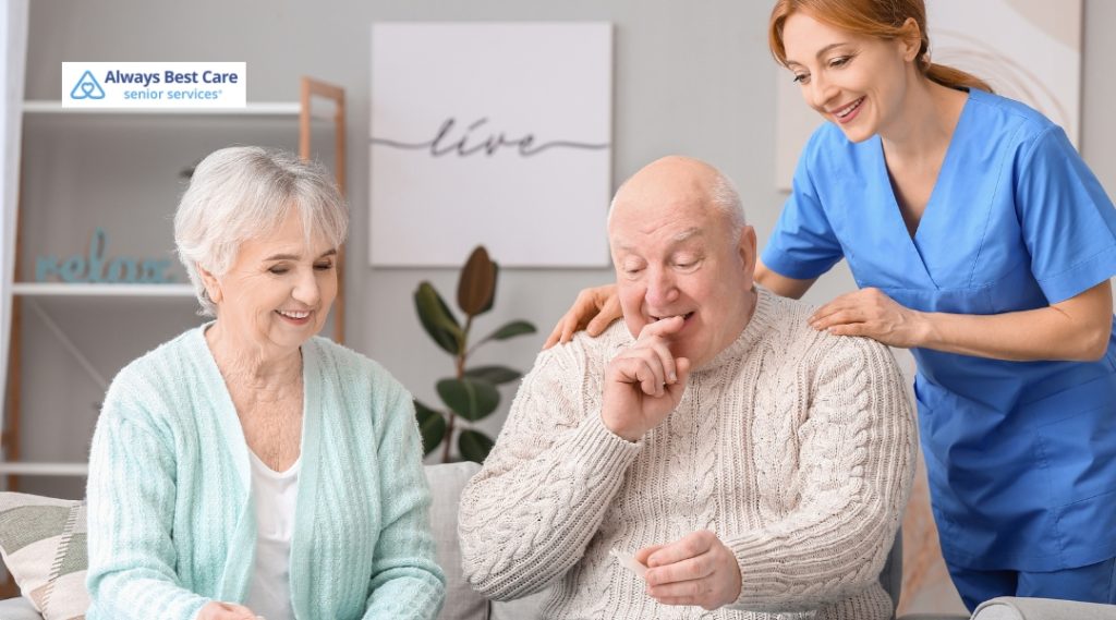 A caregiver kneels and gently holds the hands of a senior woman sitting on her bed, fostering a calm, supportive, and caring interaction in a serene home environment.