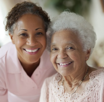 SMILING CAREGIVER AND SENIOR CLIENT SHARING A WARM MOMENT AT HOME, REFLECTING COMPASSIONATE HOME CARE SERVICES IN FITCHBURG, WI THAT PROMOTE COMFORT, DIGNITY, AND COMPANIONSHIP.