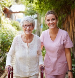 SENIOR WOMAN USING A WALKER WITH A CAREGIVER BESIDE HER OUTDOORS, SHOWING SUPPORT AND MOBILITY IN VERONA, WI.