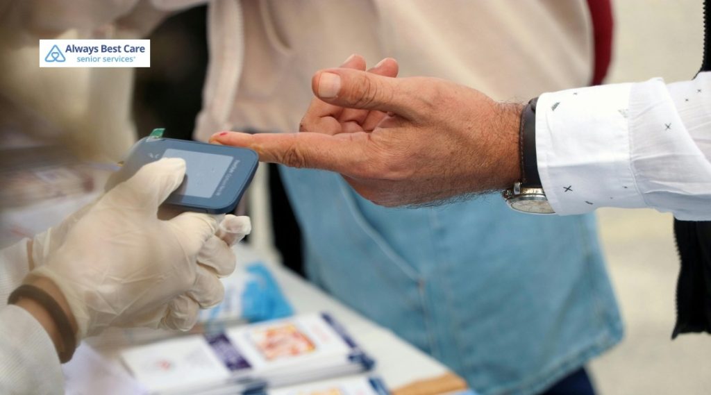 A GLOVED CAREGIVER USES A HANDHELD DEVICE TO CHECK AN OLDER ADULT’S FINGERTIP, WITH ALWAYS BEST CARE SENIOR SERVICES BRANDING IN THE CORNER.
