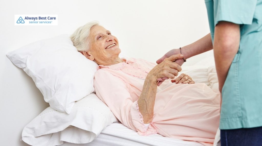 Caregiver shares a warm moment with an older woman resting in bed