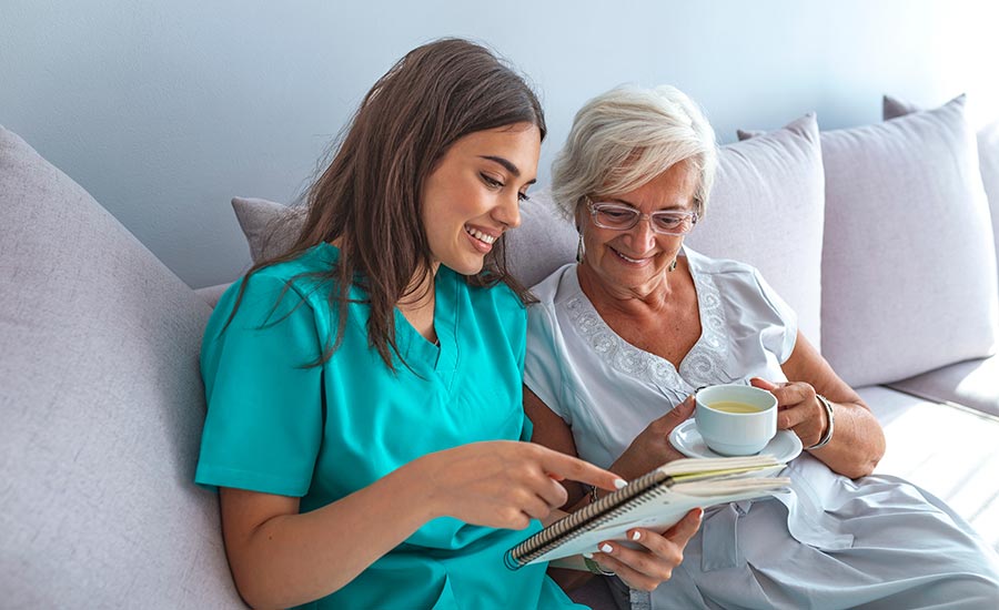 A caregiver reading a book to an elderly woman