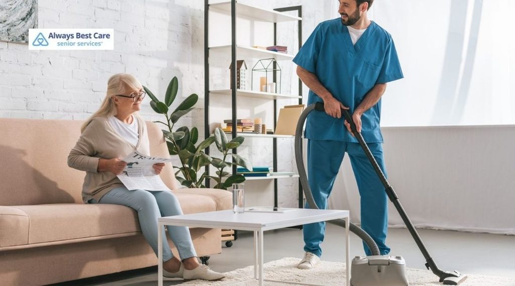 Caregiver providing light housekeeping while an older woman relaxes at home.