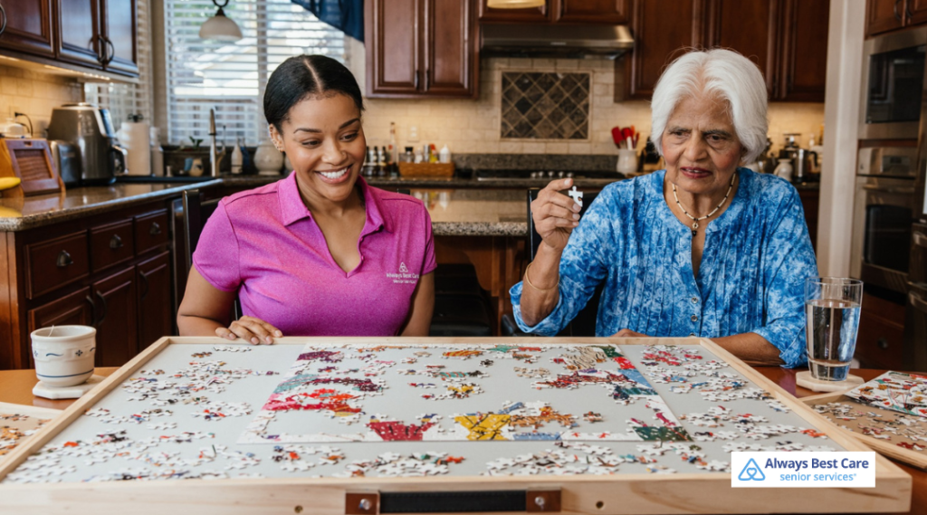 Caregiver and senior completing a puzzle together at the kitchen table, encouraging cognitive engagement and companionship.