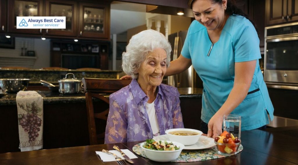 Caregiver serving soup to a senior woman who is sitting at the table