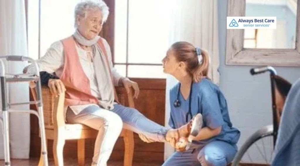 Skilled nurse supporting an older woman’s leg during an in-home mobility or rehabilitation visit.